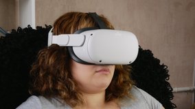 Curly-haired girl in VR glasses. Modern technological gadget. Virtual reality management tool. Plays computer games. Head close-up.