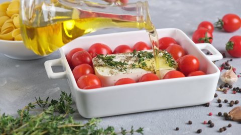 Cooking baked feta pasta. Raw ingredients before cooking: pasta, feta cheese, olive oil and cherry tomatoes with herbs and garlic. Fetapasta