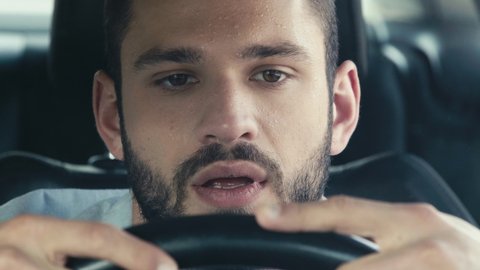 close up of sweaty man gesturing while sitting in car and holding steering wheel