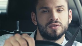 selective focus of bearded man looking at watch and holding steering wheel while driving car