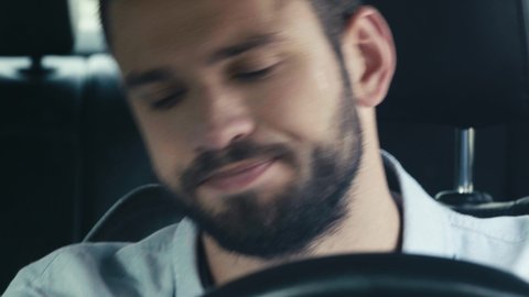 close up of sweaty man gesturing while sitting in car and looking at watch