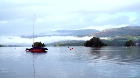 Red sailing boat on misty morning lake - wideshot on Lake Windermere, Cumbria UK