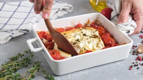 Feta cheese pasta sauce recipe step. Tomatoes drizzled with olive oil in a baking dish with a feta cheese block in the middle and sprinkled with salt and freshly ground pepper.