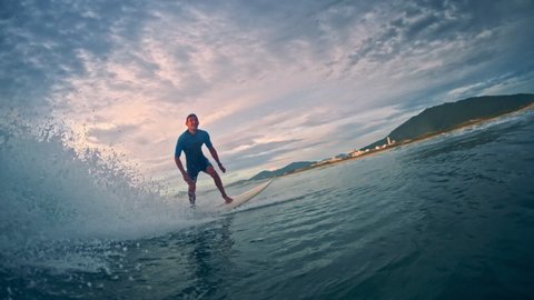 Young male surfer rides the wave at sunrise at Campeche beach break