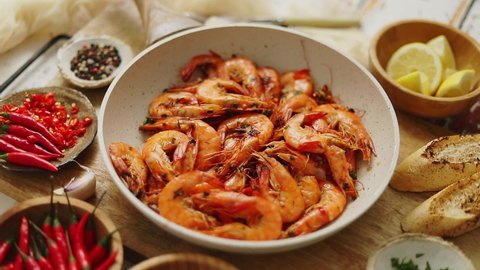 Roasted Prawns on frying pan served on white wooden cutting board