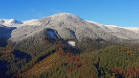 Picturesque mountain landscapes of autumn with snow near the village of Dzembronya in Ukraine Carpathians mountains. Aerial UHD 4K drone realtime video, shot in 10bit HLG and colorized
