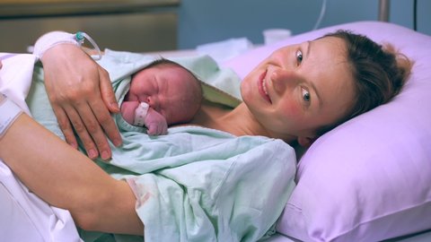 Mother and newborn. Child birth in maternity hospital. Young mom hugging her newborn baby after delivery. Woman giving birth. First moments of baby life after labor.