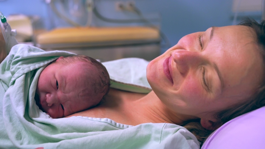 Mother and newborn. Child birth in maternity hospital. Young mom hugging her newborn baby after delivery. Woman giving birth. First moments of baby life after labor. Royalty-Free Stock Footage #1069668496