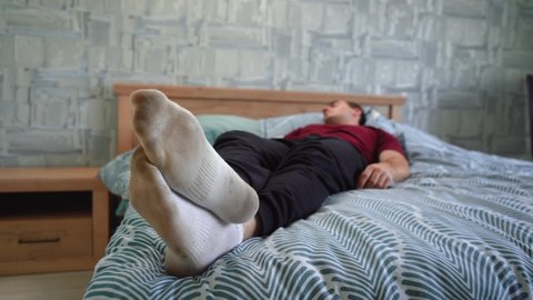 a man lies on the bed in dirty socks