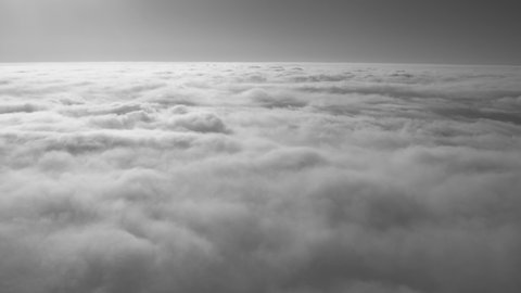View from flying high in heaven airplane. Sunny peaceful fluffy white clouds and blue sky with horizon line. Black and white 4k stock video footage