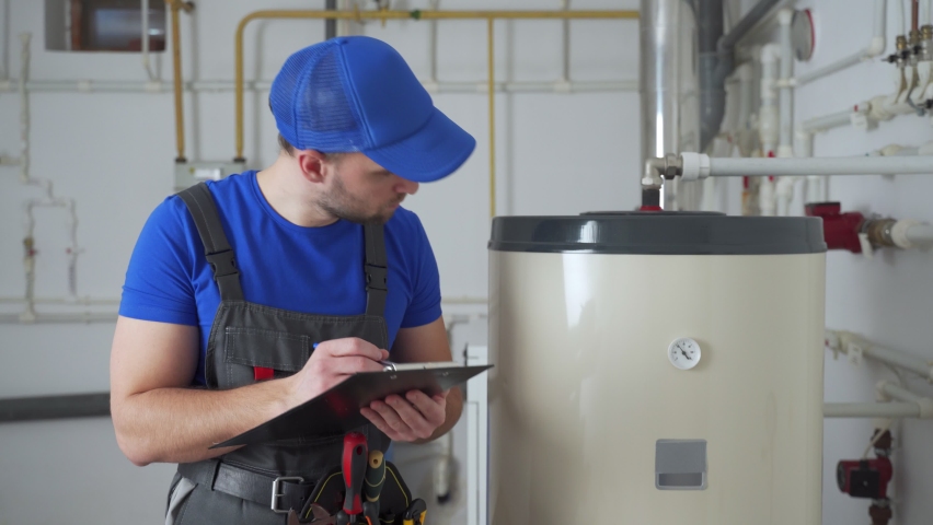 Technician servicing an hot-water heater. Man check equipment of the boiler-house - thermometer.  Royalty-Free Stock Footage #1069681648