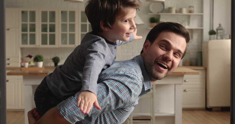 Happy father piggyback riding on his back little 5s preschool son, cheerful family playing together in cozy living room. Weekend leisure, active game, playtime with children at home, have fun concept Royalty-Free Stock Footage #1069685581