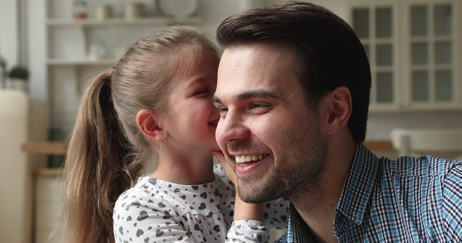 Close up view loving father listens to little cheery daughter whispers gossip in daddy ear, tells secret information. Honesty, trustworthy relations and understanding between parent and child concept | Shutterstock HD Video #1069685617