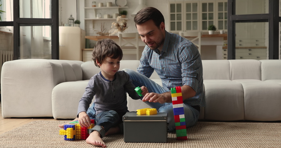 Caring dad and preschool son play colorful blocks set sit on floor in living room spend playtime together enjoy pastime and game at home. Loving father teach kid, favourite hobby and leisure concept Royalty-Free Stock Footage #1069685632