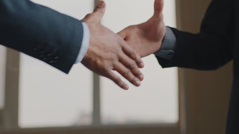 Close up male hands multiethnic business men african and caucasian colleagues in suit handshake in office. Unrecognizable employer hire ethnic vacancy candidate shakes hands, makes congratulations 