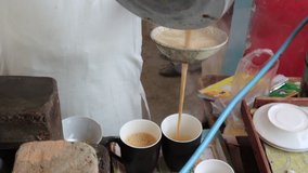 Chai wala (tea seller) pours milk and other ingredients, Chai Making Traditional Style In Pakistan 4k Clip