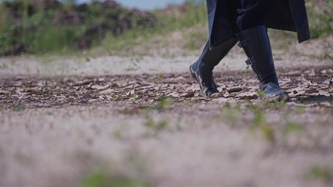 A man in black boots and a raincoat walks across the dry, cracked ground. Cool cinematic shots