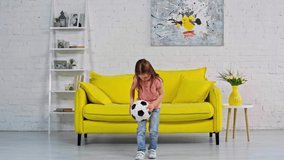 cute kid playing with soccer ball in living room