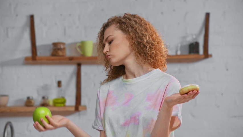 Pensive woman holding apple and doughnut