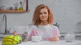 Smiling woman pouring cereals in bowl in kitchen