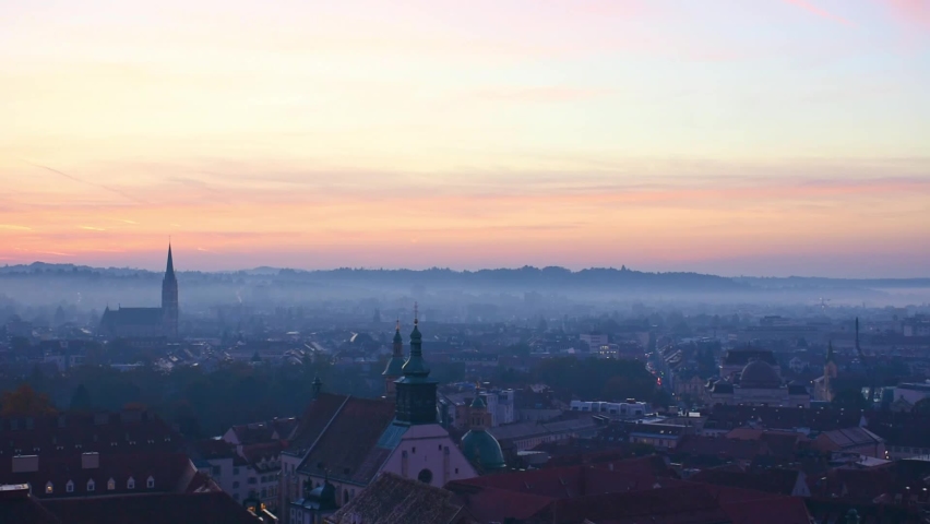 Cityscape of Graz with Church of the Sacred Heart of Jesus and historic buildings rooftops in Graz, Styria region, Austria, at sunrise