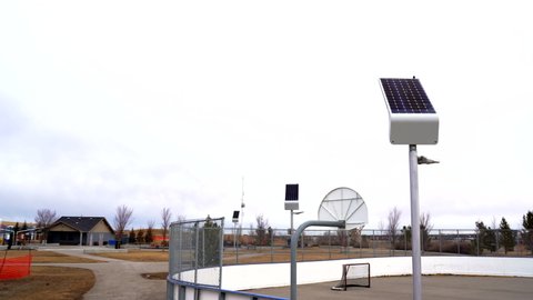 An outdoor hockey rink and basketball court outfitted with solar panel charging lights in the sustainable community of Airdrie Alberta Canada.