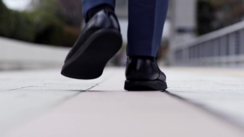 The feet of a Japanese businessman walking outside