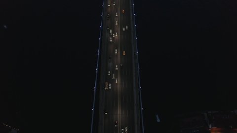 Birds Eye Top Down View of Bridge at Night with Car traffic looking up revealing City Skyline Silhouette, Aerial tilt up