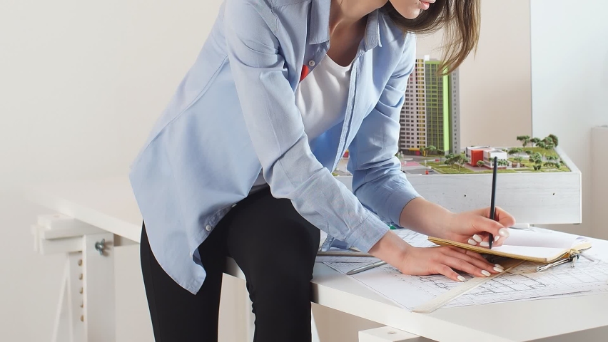 Young professional architect at work in the office. A young woman uses a pencil and compasses in her work, works in an office as a designer, architect.