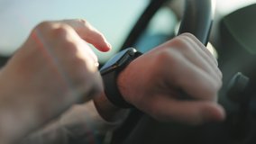 Close-up male hands using modern smart watch in car. Man watch notification. Male hand with a smartwatch holds the steering wheel. Businessman driving car at sunset - Powered by Shutterstock - Get 15% off with code: PIKWIZARD15
