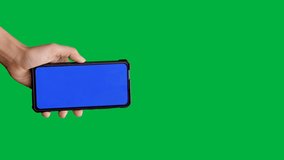 Vertical video, Woman hand holding and touching screen the smartphone with blue screen on chroma key green screen background.