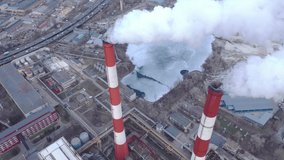 An industrial area with a large red and white chimney, thick white smoke is pouring from the factory chimney, unlike the sun. Environmental pollution: pipe with smoke. Drone video.