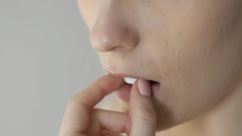 close up of a woman taking a white zinc pill and drinking water.