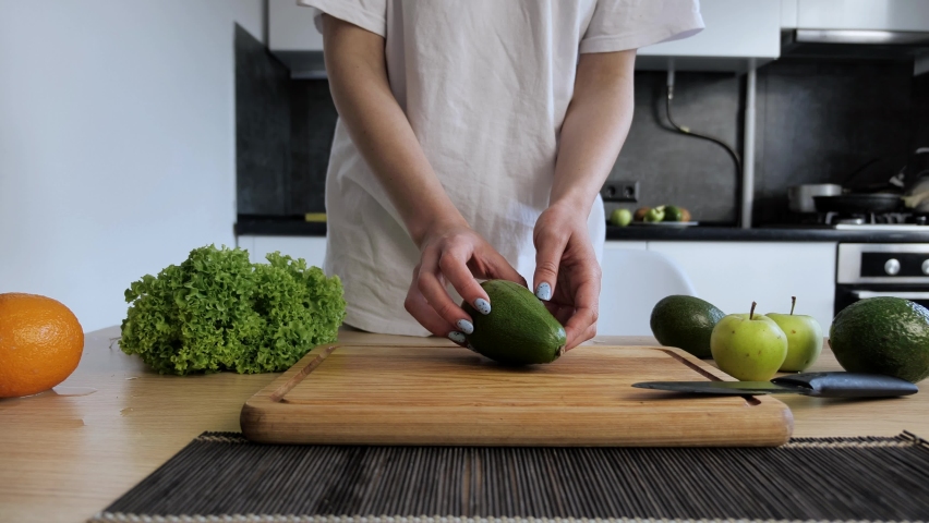 Chef woman showing hands fresh avocado in the modern kitchen interior. Conception healthy vegan food.