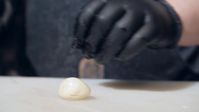 A man cuts garlic with a knife. Cutting vegetables close-up. Food preparation. The cook in black gloves is cutting vegetables. Kitchen affairs. Chef's job. Cooking vegetable dishes.