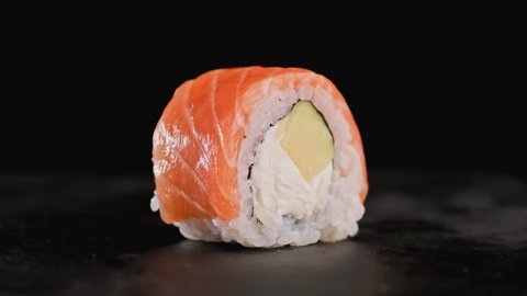 Fresh sushi rolls rotating at black background. Close-up shot of philadelphia rolls. Sushi from fish, salmon, rice, avocado. Delecious food. Traditional asian food. 4K, UHD