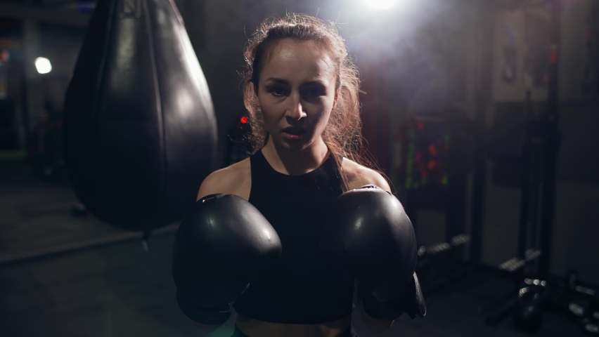 Portrait of female boxer standing at dark gym, looking intensely at the camera and screaming Royalty-Free Stock Footage #1069728376