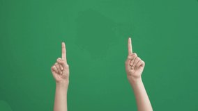 Kid hands raising up and fingers pointing up over empty chroma key green screen background. Communication with no talking, gesture concept