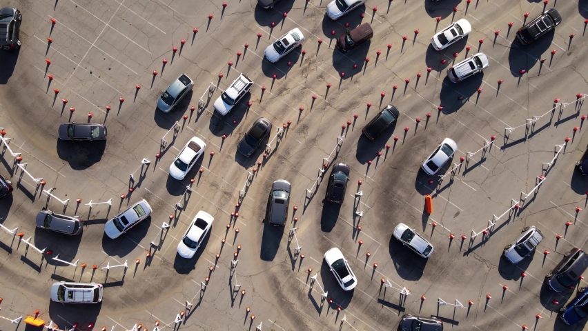 Aerial shot of 1000’s of people in cars waiting in line at a drive-through testing site to be tested for Coronavirus or to receive the vaccine. | Shutterstock HD Video #1069734076