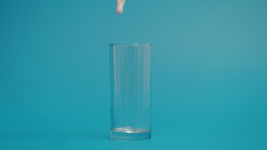 Super Slow Motion of Pouring Milk in Transparent Glass, Blue Background  | Shutterstock HD Video #1069746691