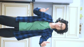 vertical video. handsome curly guy dancer cheerfully dancing at home in the kitchen .