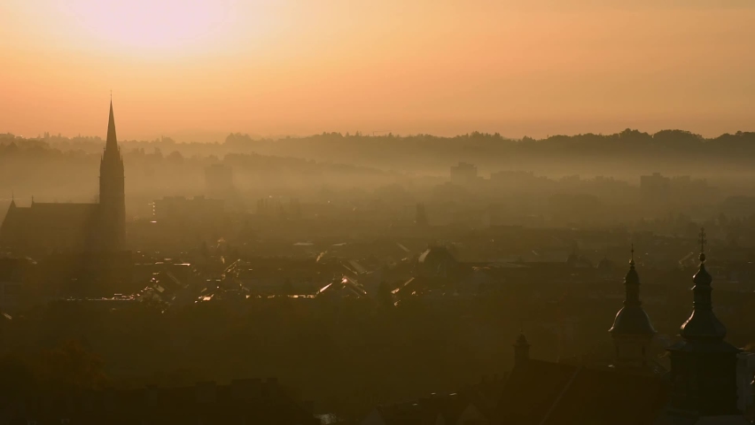 Cityscape of Graz with Church of the Sacred Heart of Jesus and historic buildings rooftops in Graz, Styria region, Austria, at sunrise