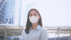 Asian businesswoman wearing protective Covid-19 face covering mask om urban building setting, city life during pandemic - Powered by Shutterstock - Get 15% off with code: PIKWIZARD15