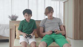 Happiness family with father and son playing video game with joystick on sofa with fun in the room at home, dad and boy doing activity with excited together, leisure with entertainment, indoor.