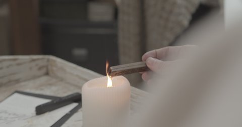 A person warming sealing wax with a burning candle, preparing to seal a letter. Handheld shot.