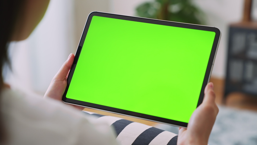 Close up of woman holding in hands a digital tablet with green screen for internet online, chroma key screen for advertising.