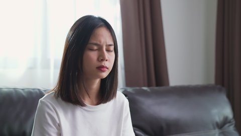 Tired young Asian woman sitting and have a headache because of migraine.