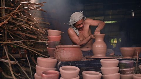 Craftman making pottery from wet clay on wheel