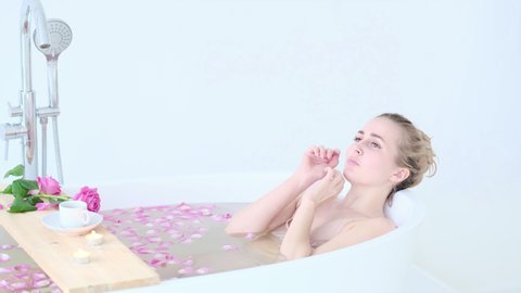 Beautiful Caucasian Blonde Girl In Bikini Lying In Flower Bath In Resort Day Spa Salon. Skin Care Therapy. Concept young woman relaxing in the bathtube. Slow motion video. stock footage