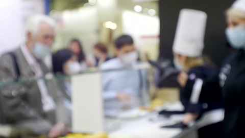 blurred business background. Chef and customers of a cafeteria or restaurant communicate behind a glass counter. Silhouettes of unrecognizable people inside a large light hall